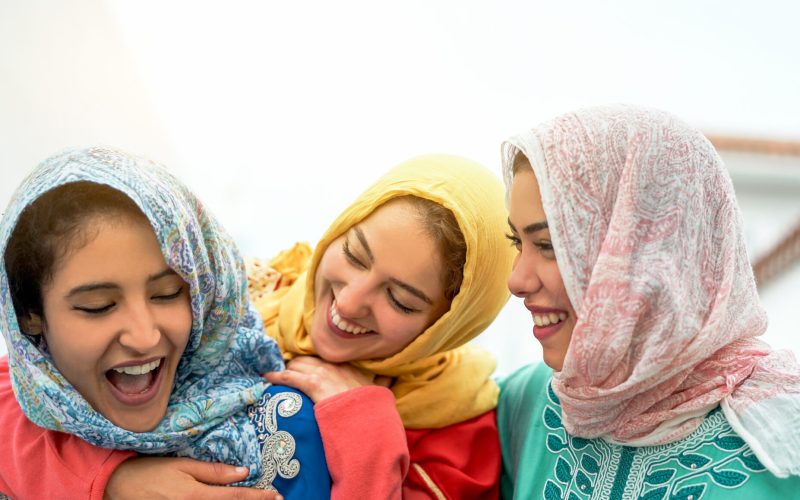 Happy arabian women having fun in the city - Young muslim girls spending time and laughing together outdoor - Concept of youth lifestyle people, culture and religion