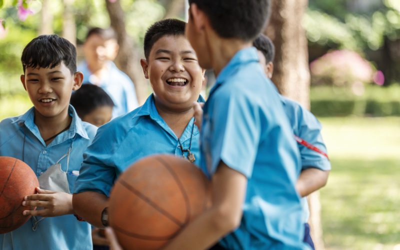 Group of children with basketballs having fun outside on the school ground during physical training class